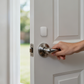 Hand opening a door with a white Multi-State Sensor P100 mounted above the door handle.