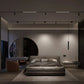 Modern bedroom with a bed, armchair, and minimal decor in a dimly lit room.