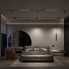 Modern bedroom with a bed, armchair, and minimal decor in a dimly lit room.