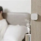 Temperature & Humidity Sensor on a wall next to a bed with a person lying in bed in the background