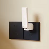 Aqara Hub M100 attached to a wall electrical socket on a beige wall.