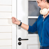 Person in a blue hoodie opening a white door