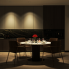 A side-by-side before and after comparison of a dining room in low light versus illuminated lighting. The left side is labeled 'Before' and is quite dark, while the right side is labeled 'After' and shows the dining table, chairs, and cabinetry more clearly with warm ambient lighting.