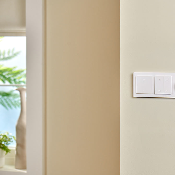 White light switch panel on a beige wall with a blurred outdoor background